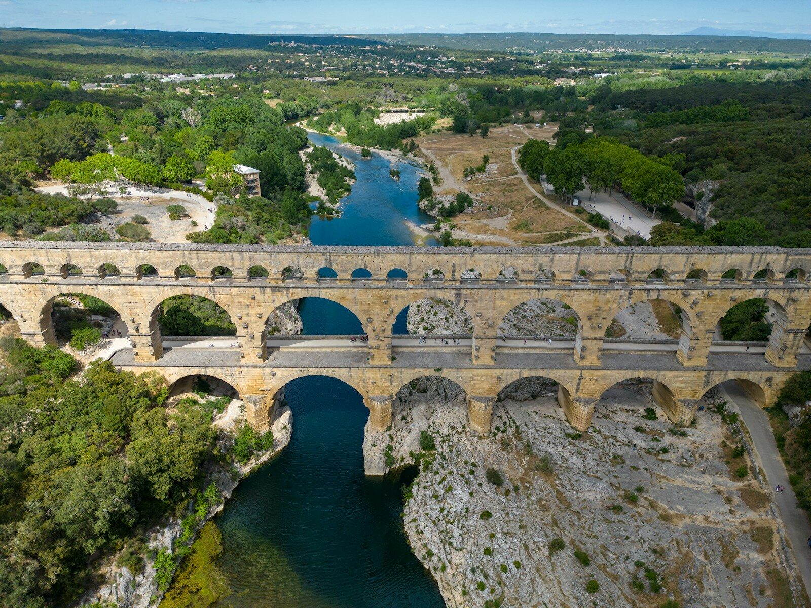 Le pont du Gard a stone bridge over a river surrounded by trees